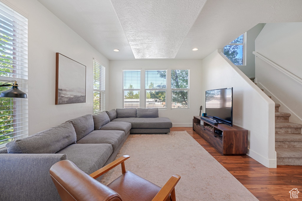 Living room with a textured ceiling, dark hardwood / wood-style flooring, and a wealth of natural light