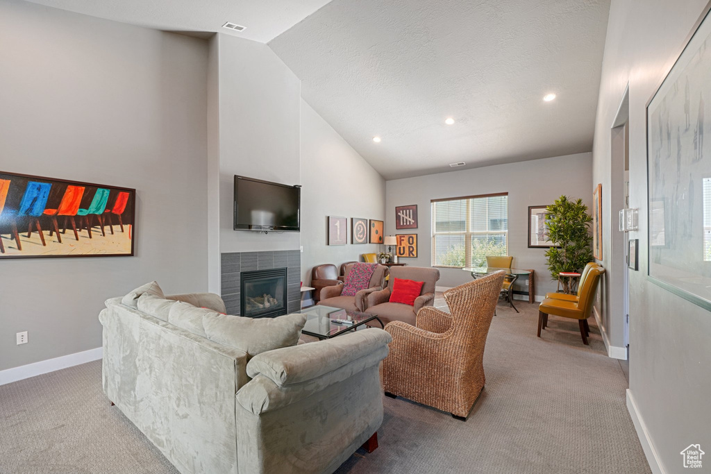 Living room featuring light colored carpet, a fireplace, and vaulted ceiling