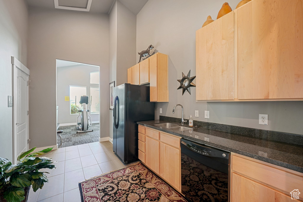 Kitchen with sink, high vaulted ceiling, black appliances, light tile patterned floors, and light brown cabinetry