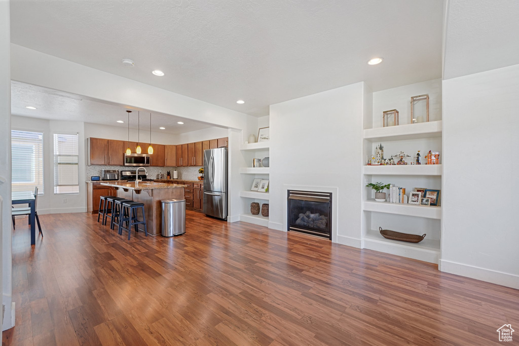 Living room featuring a textured ceiling, dark hardwood / wood-style floors, built in features, and sink