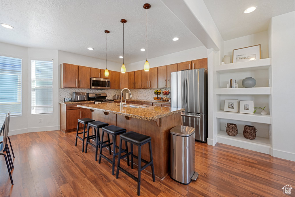 Kitchen featuring a textured ceiling, dark hardwood / wood-style floors, sink, hanging light fixtures, and appliances with stainless steel finishes