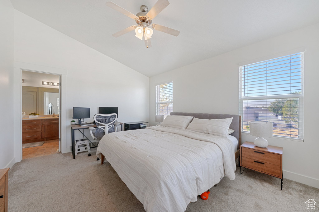 Bedroom featuring vaulted ceiling, light carpet, ceiling fan, and ensuite bath