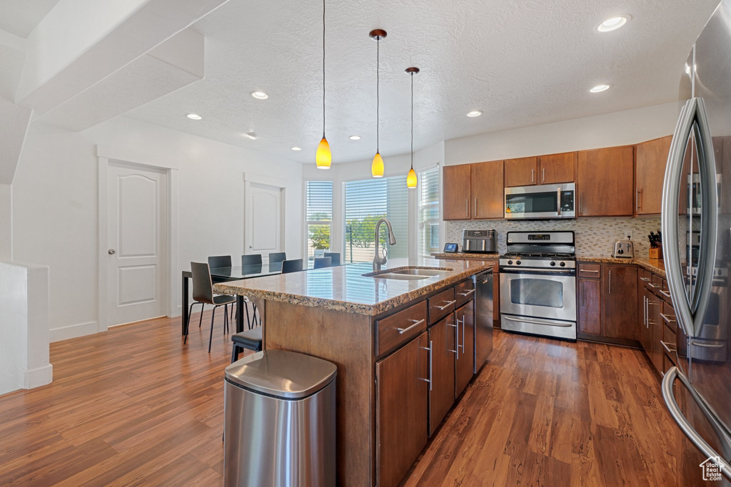 Kitchen featuring an island with sink, appliances with stainless steel finishes, sink, and dark hardwood / wood-style flooring