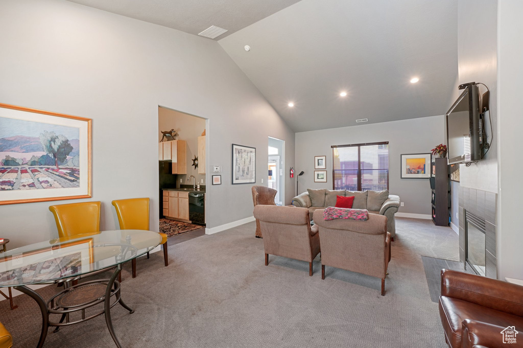 Living room featuring light carpet, sink, and high vaulted ceiling