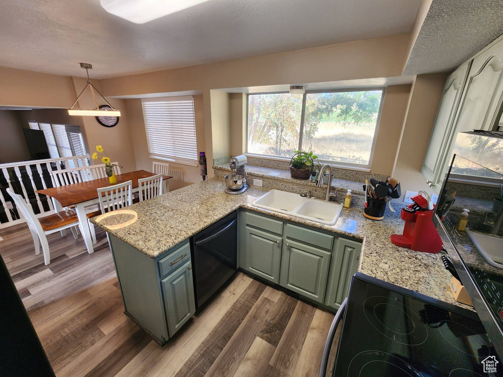 Kitchen featuring black dishwasher, hardwood / wood-style floors, sink, and kitchen peninsula