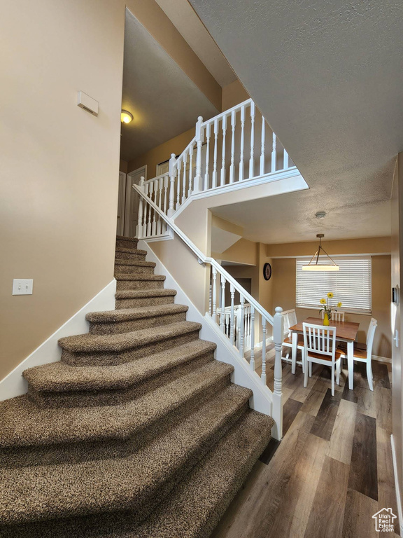 Stairway featuring a textured ceiling and hardwood / wood-style flooring