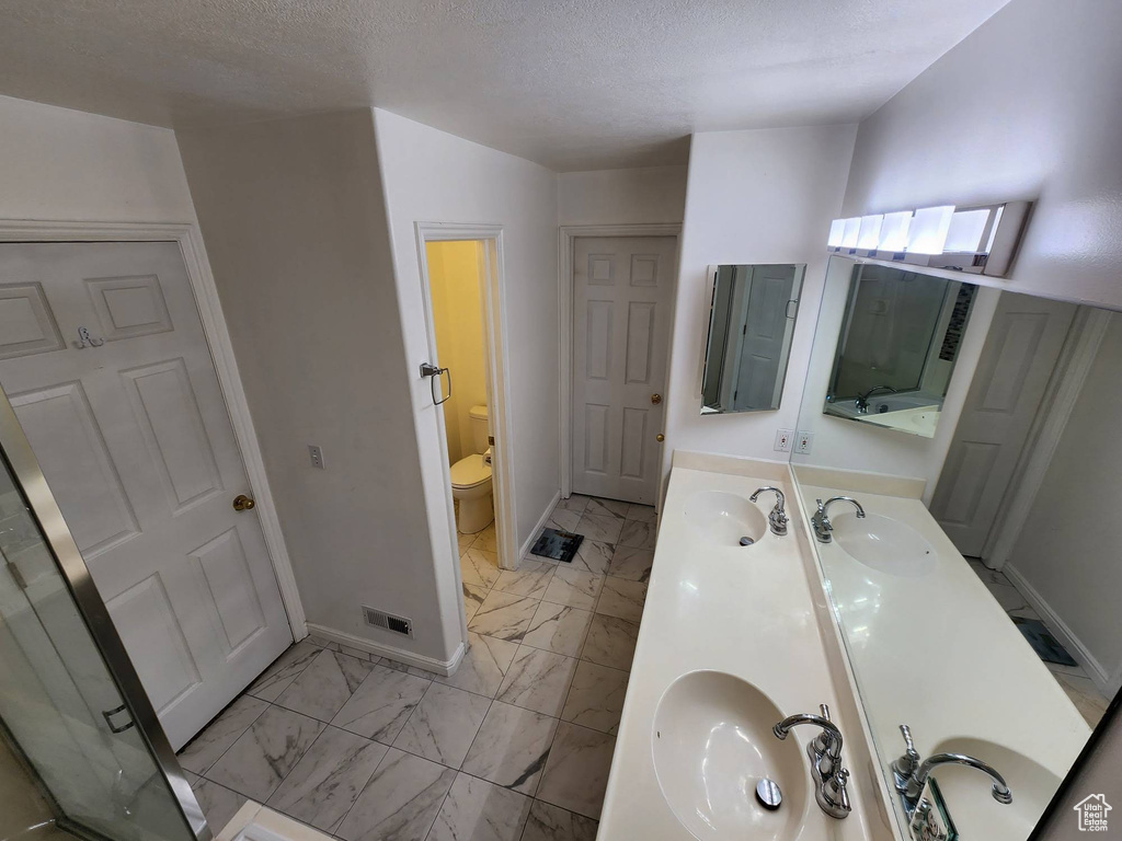 Bathroom with a textured ceiling, vanity, and toilet