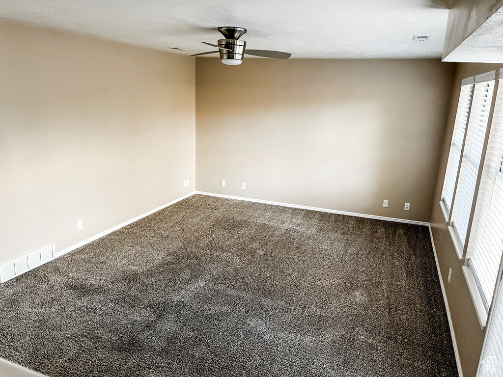 Carpeted empty room featuring a healthy amount of sunlight and ceiling fan