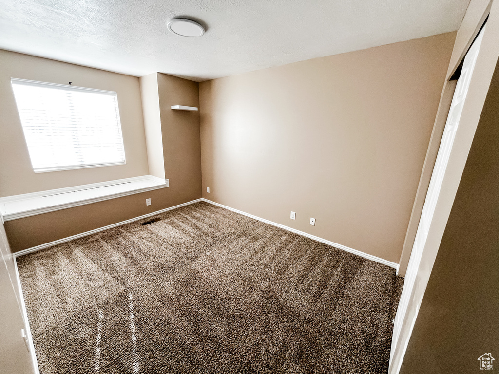 Carpeted empty room with a textured ceiling