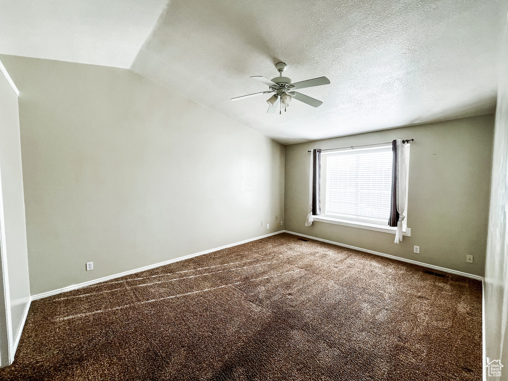 Carpeted empty room with lofted ceiling, a textured ceiling, and ceiling fan