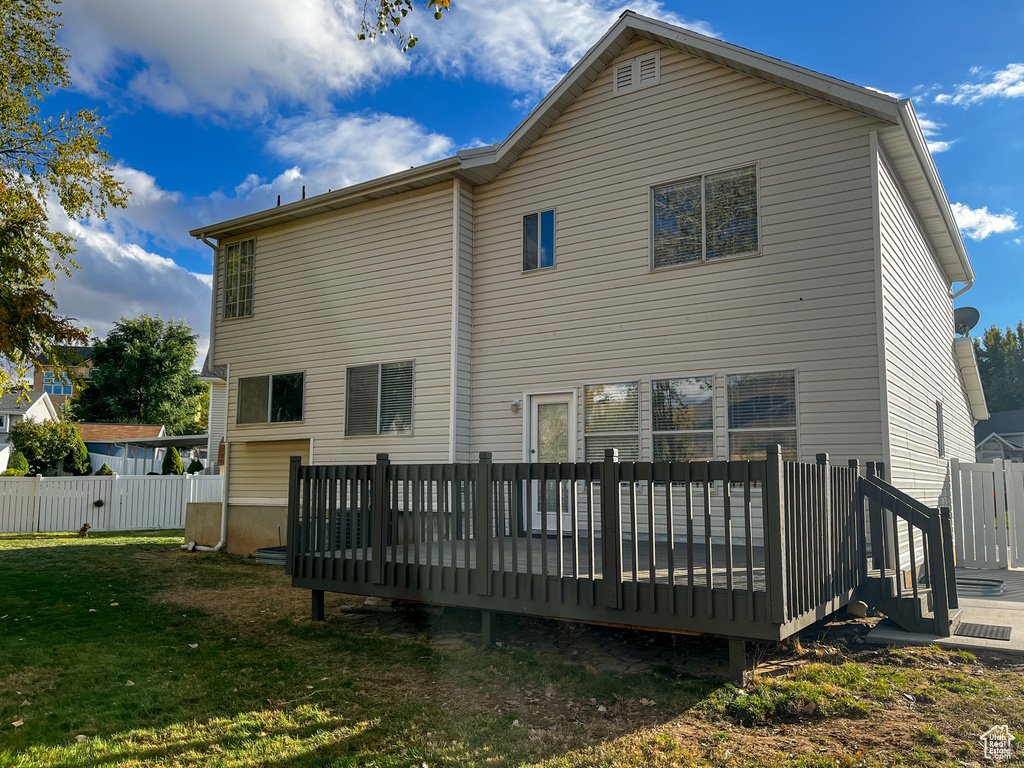 Rear view of house featuring a deck and a lawn