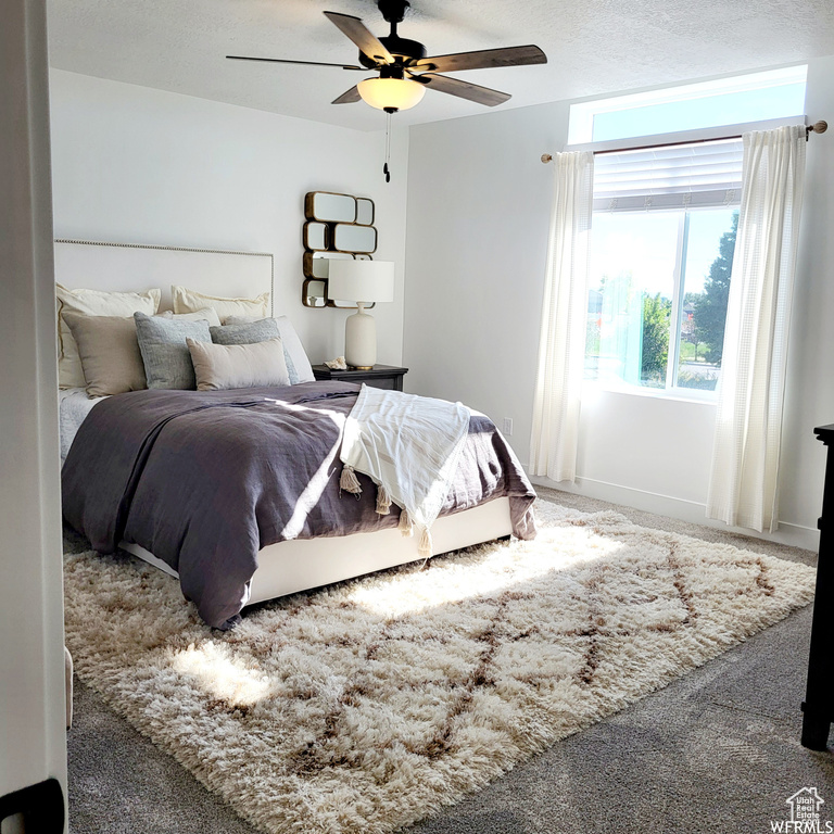 Carpeted bedroom featuring ceiling fan and a textured ceiling