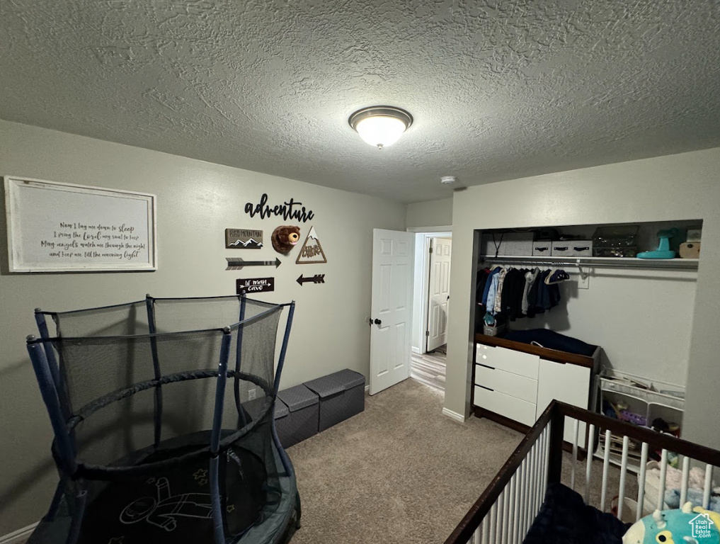 Bedroom with a textured ceiling, a closet, and carpet flooring