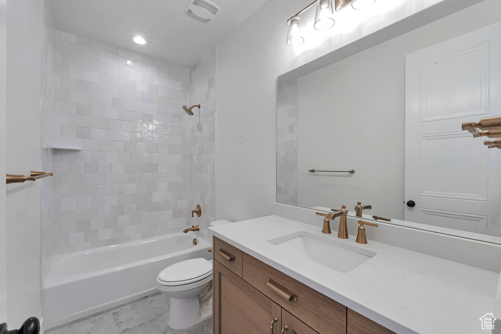 Full bathroom featuring tiled shower / bath combo, vanity, and toilet