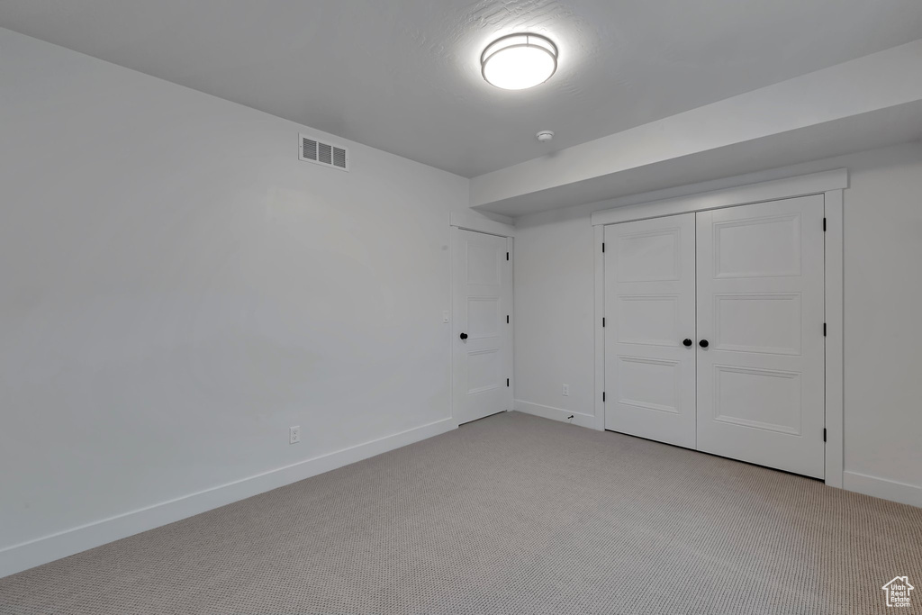 Unfurnished bedroom featuring a closet and light colored carpet