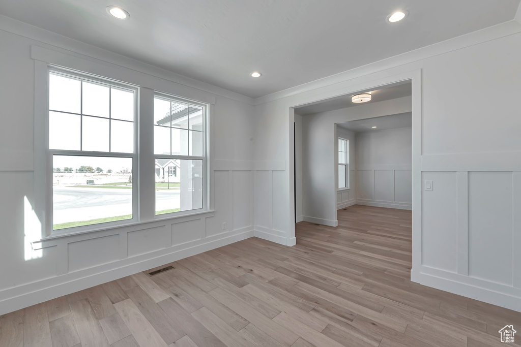 Empty room with light hardwood / wood-style floors and crown molding