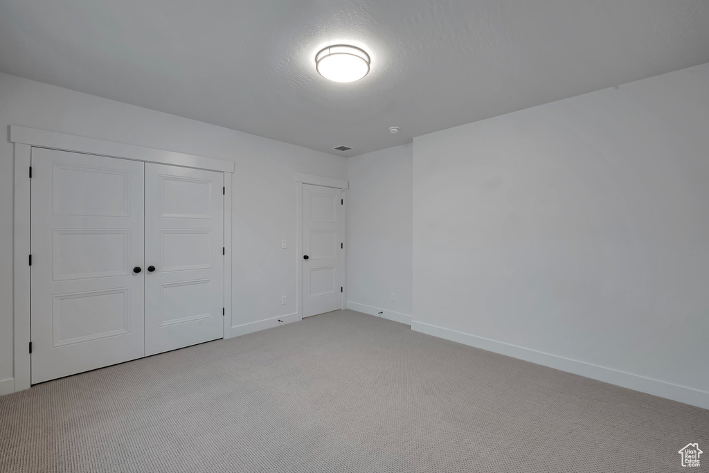 Unfurnished bedroom with light carpet and a closet