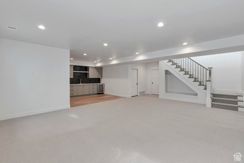 Unfurnished living room featuring light colored carpet and sink