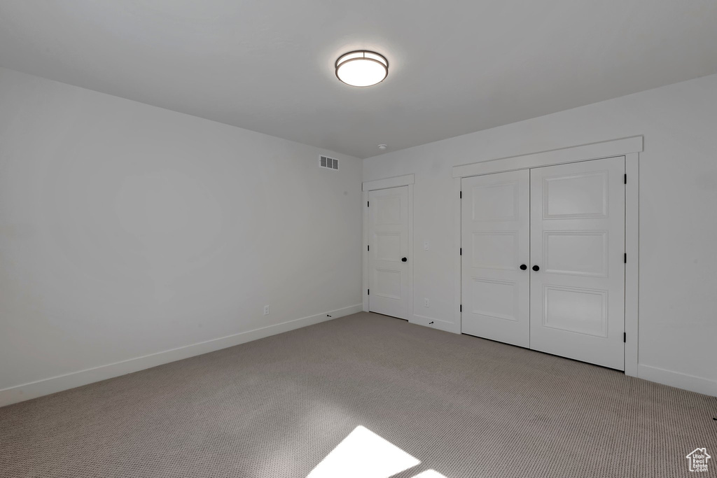 Unfurnished bedroom with light carpet and a closet