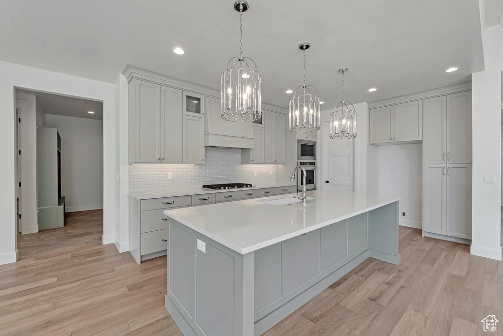 Kitchen featuring light hardwood / wood-style floors, sink, stainless steel appliances, and a spacious island