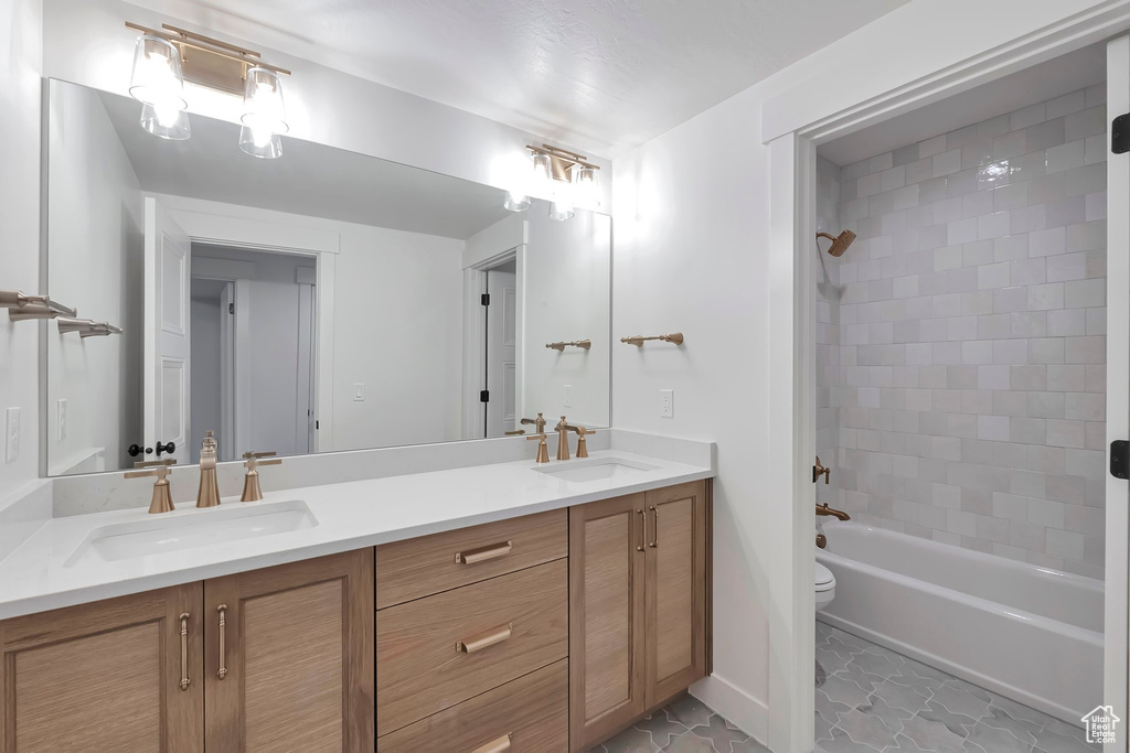 Full bathroom with vanity, tiled shower / bath combo, and toilet