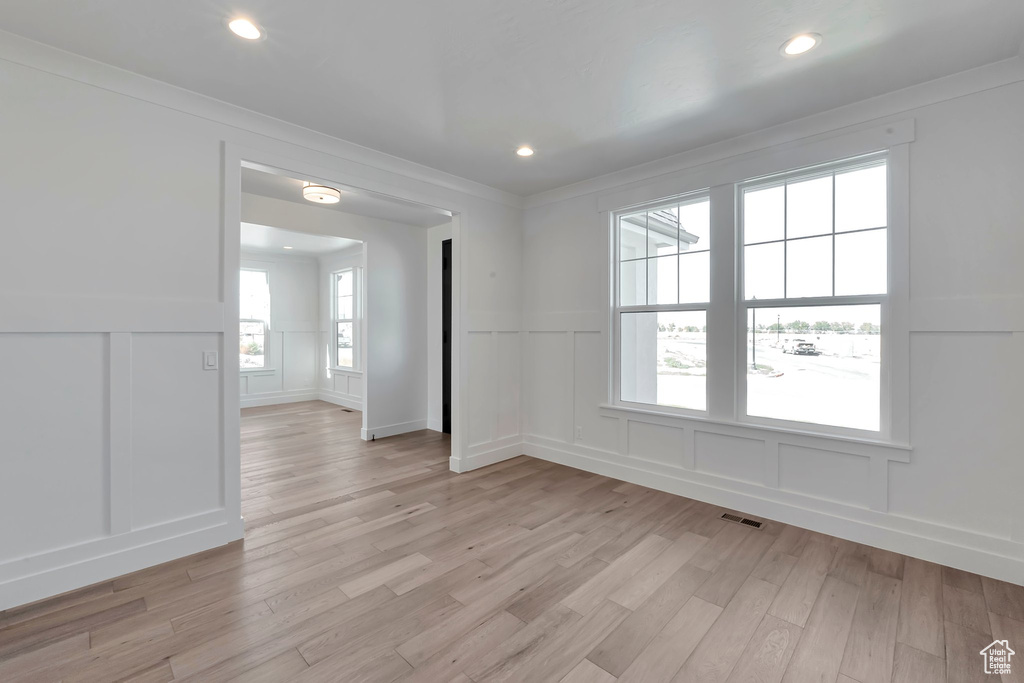 Empty room featuring light wood-type flooring and crown molding