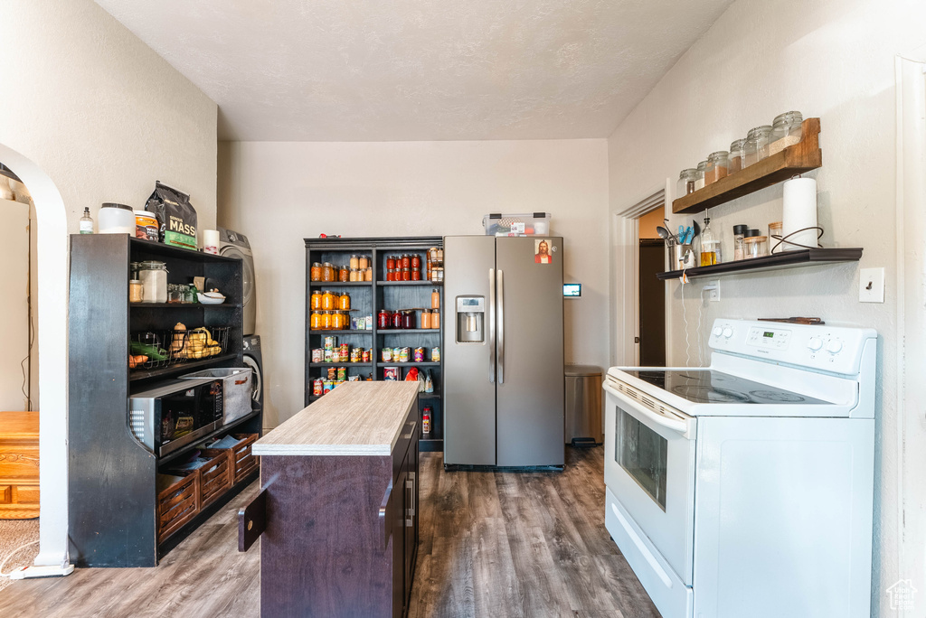 Kitchen featuring dark brown cabinetry, stainless steel refrigerator with ice dispenser, a center island, white electric stove, and dark hardwood / wood-style flooring