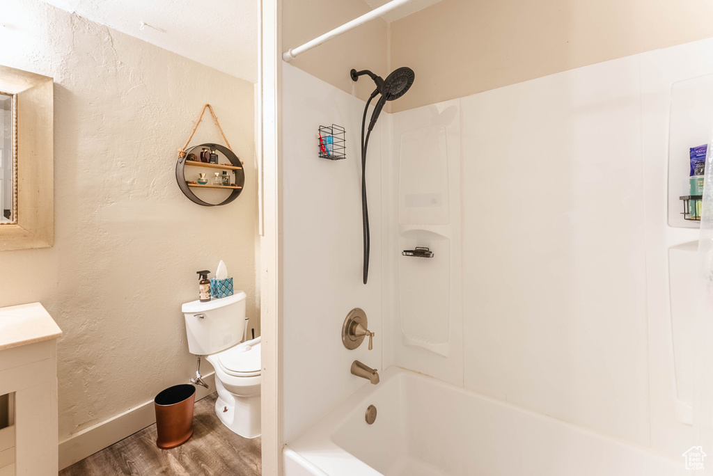 Full bathroom featuring wood-type flooring,  shower combination, vanity, and toilet