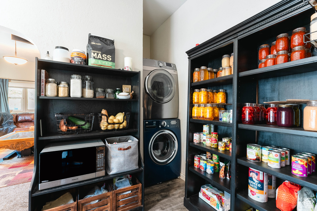 Clothes washing area featuring stacked washer / drying machine and dark hardwood / wood-style flooring