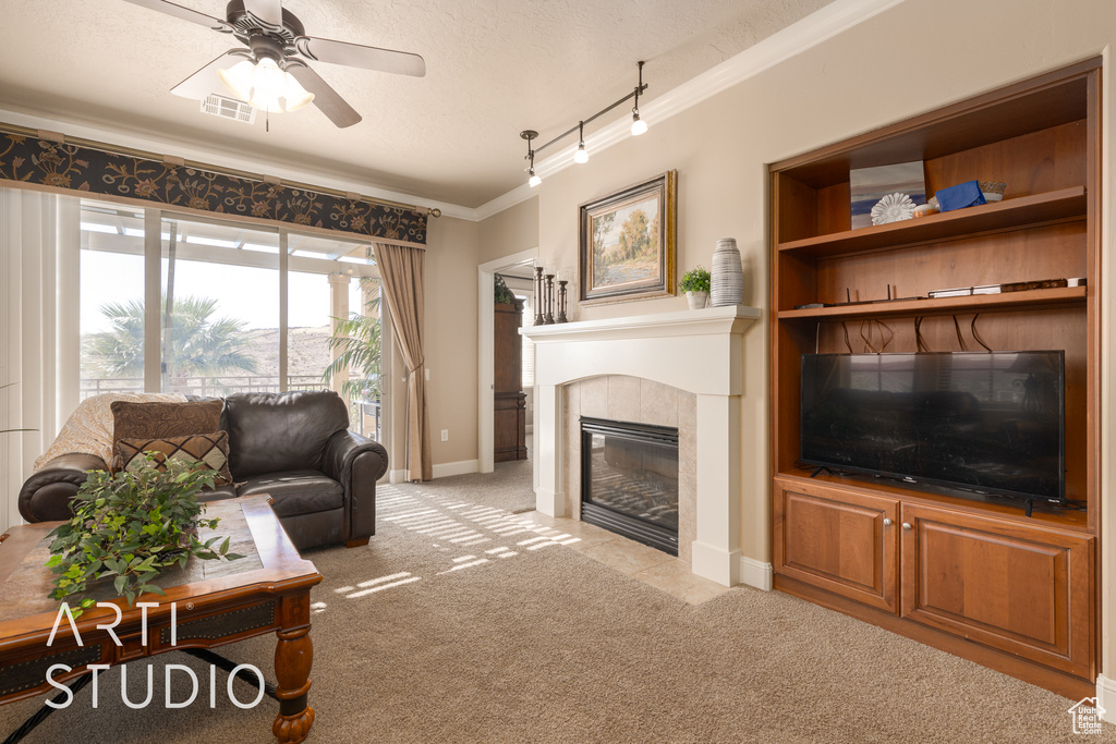 Carpeted living room with ceiling fan, ornamental molding, a textured ceiling, track lighting, and a fireplace