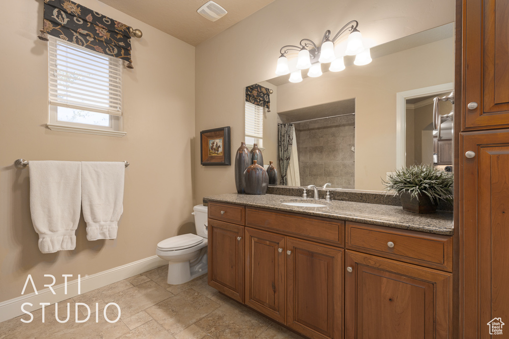 Bathroom featuring a shower with shower curtain, vanity, and toilet