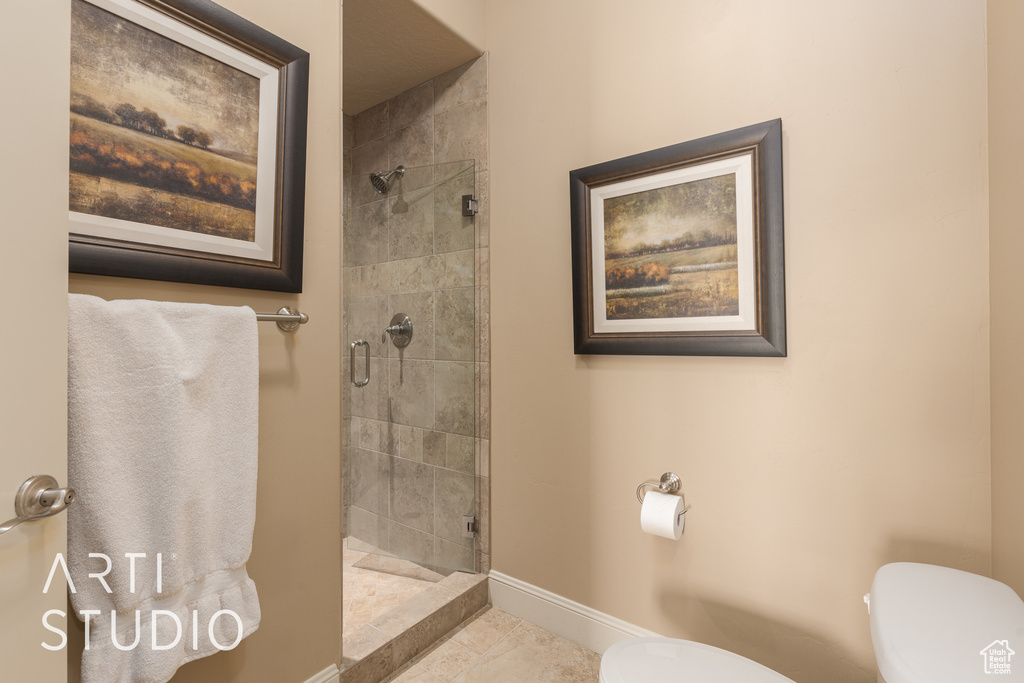 Bathroom featuring toilet, tile patterned floors, and a shower with shower door