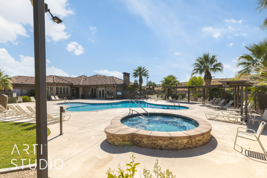 View of swimming pool featuring a hot tub and a patio area