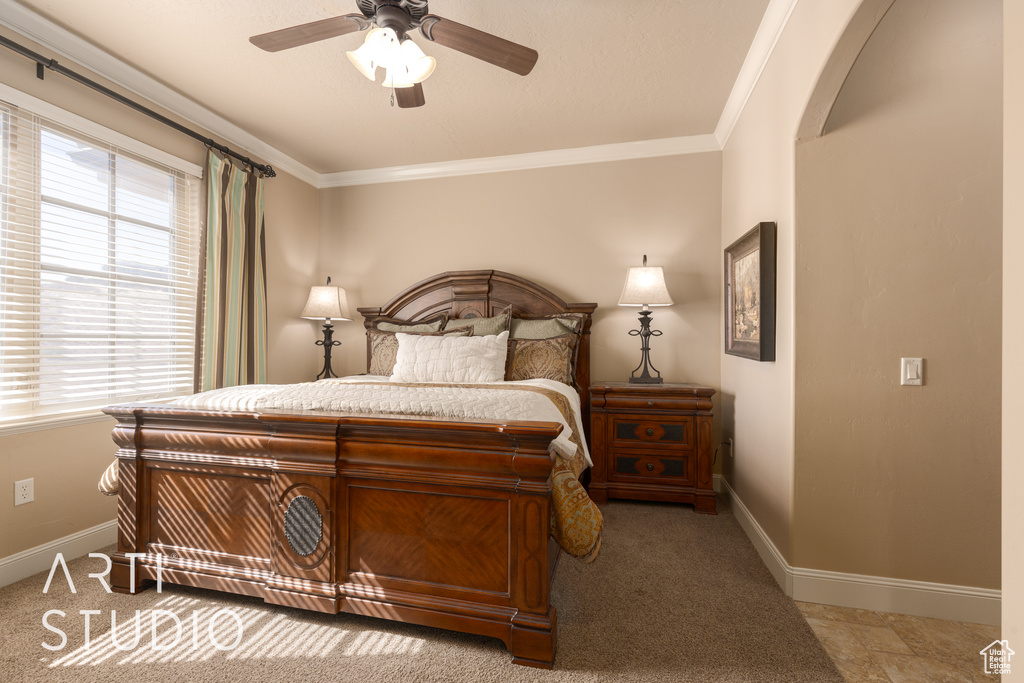 Bedroom with ceiling fan, light colored carpet, and ornamental molding