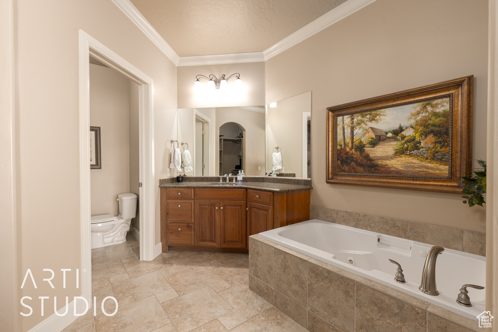 Bathroom with vanity, ornamental molding, a relaxing tiled tub, and toilet