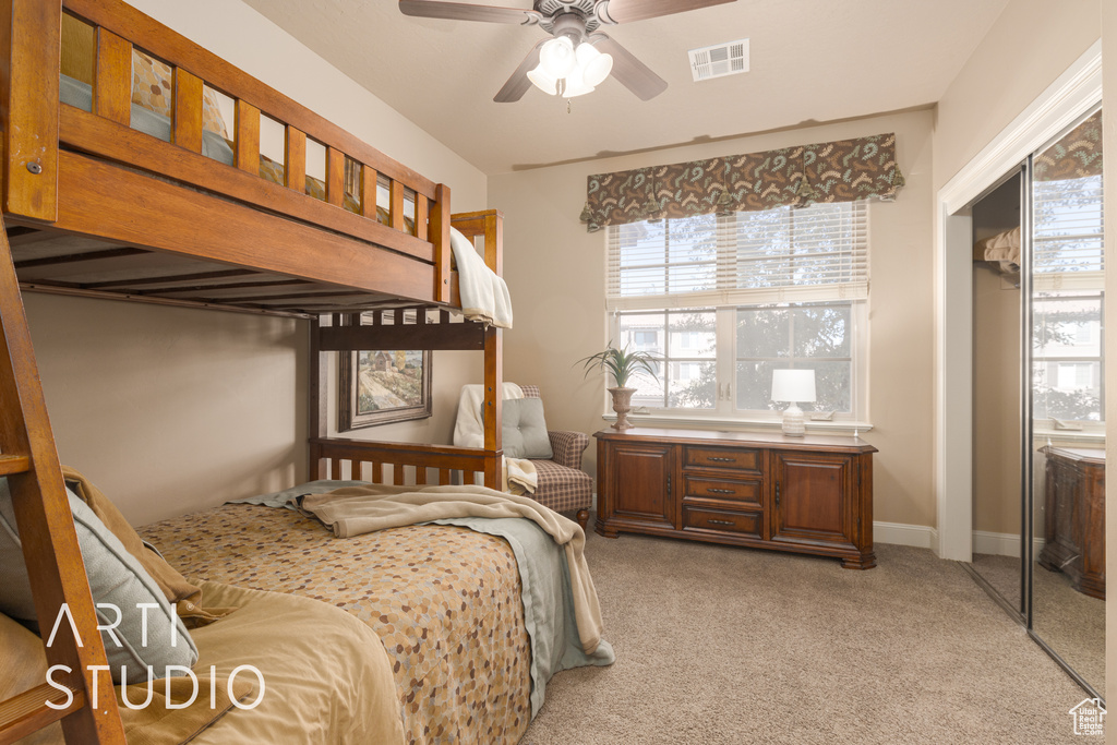 Carpeted bedroom featuring ceiling fan, a closet, and multiple windows