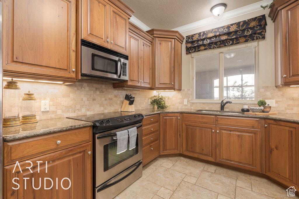 Kitchen with ornamental molding, tasteful backsplash, stone countertops, a textured ceiling, and stainless steel appliances