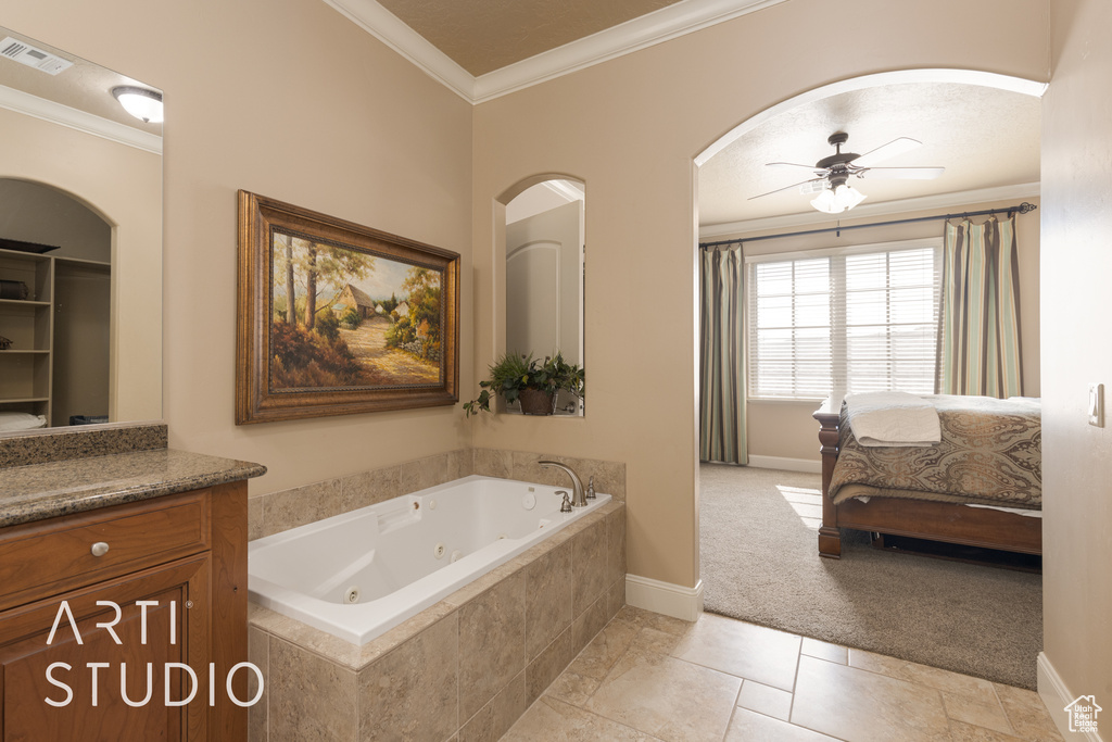 Bathroom with tiled tub, vanity, crown molding, tile patterned flooring, and ceiling fan