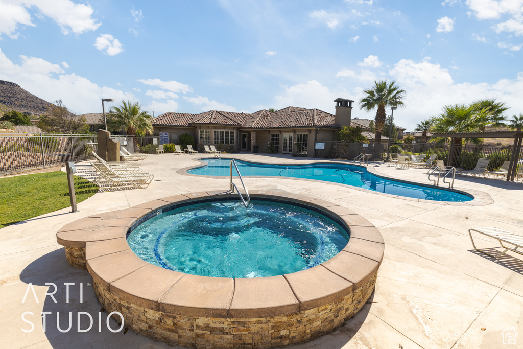 View of swimming pool with a patio, a hot tub, and a mountain view