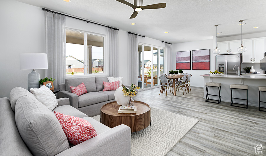 Living room with light hardwood / wood-style floors and ceiling fan