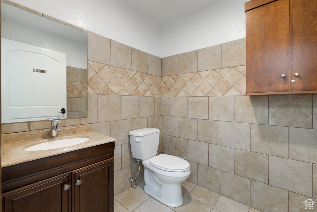 Bathroom featuring tile walls, tile patterned flooring, vanity, and toilet