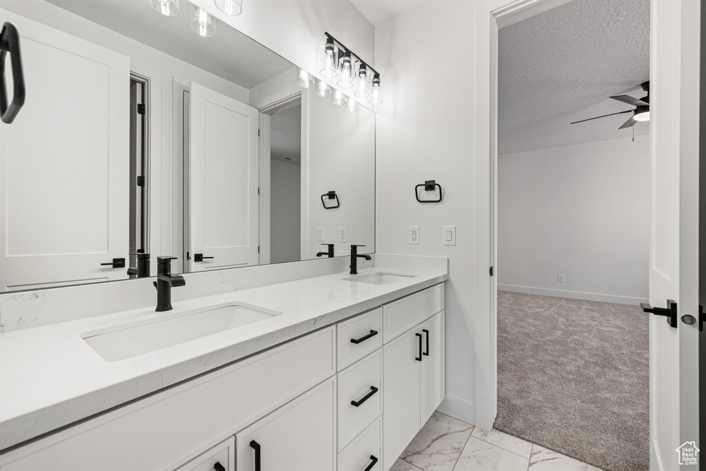 Bathroom with ceiling fan, a textured ceiling, and vanity