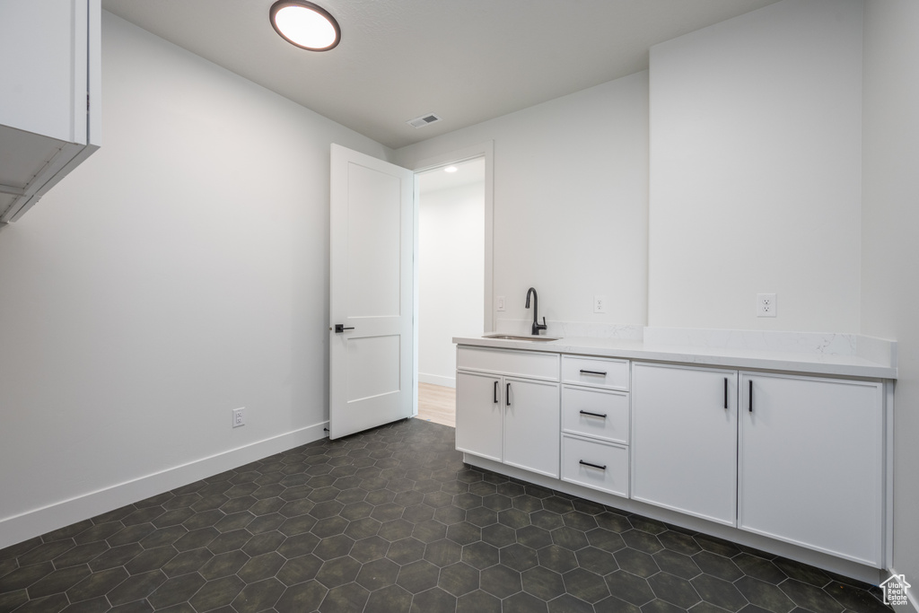 Bar with white cabinetry, sink, and dark tile patterned flooring