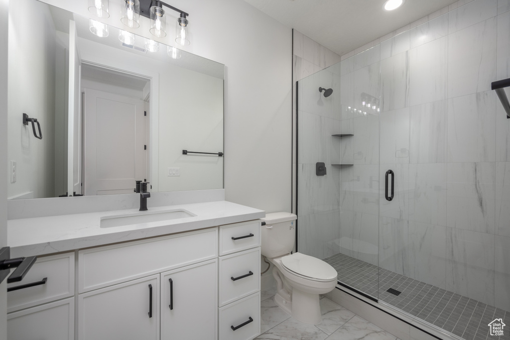 Bathroom featuring a shower with shower door, vanity, and toilet