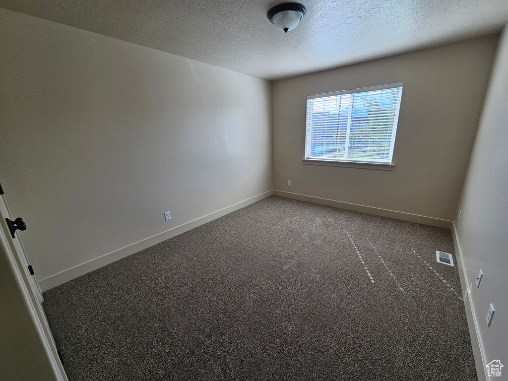 Carpeted empty room featuring a textured ceiling