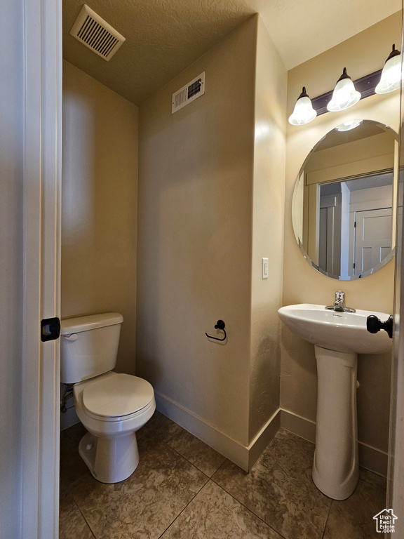 Bathroom with a textured ceiling, tile patterned floors, and toilet