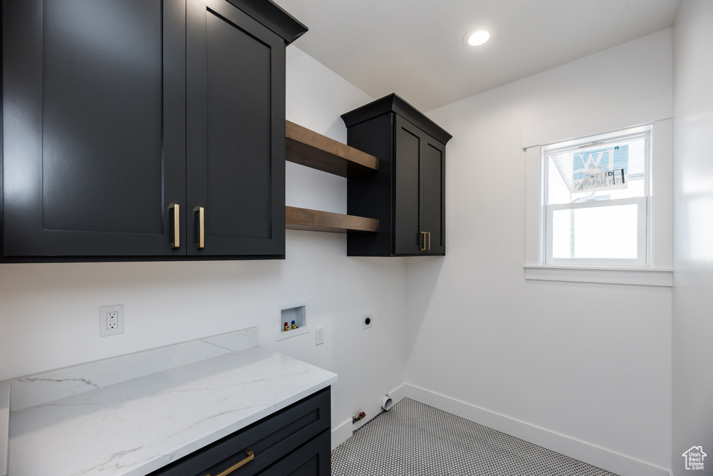 Laundry room with light tile patterned floors, hookup for a gas dryer, cabinets, hookup for a washing machine, and electric dryer hookup