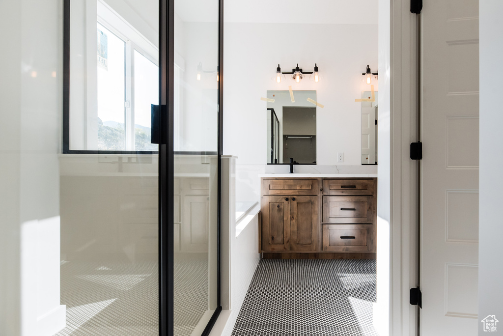 Bathroom featuring vanity, plus walk in shower, and tile patterned flooring