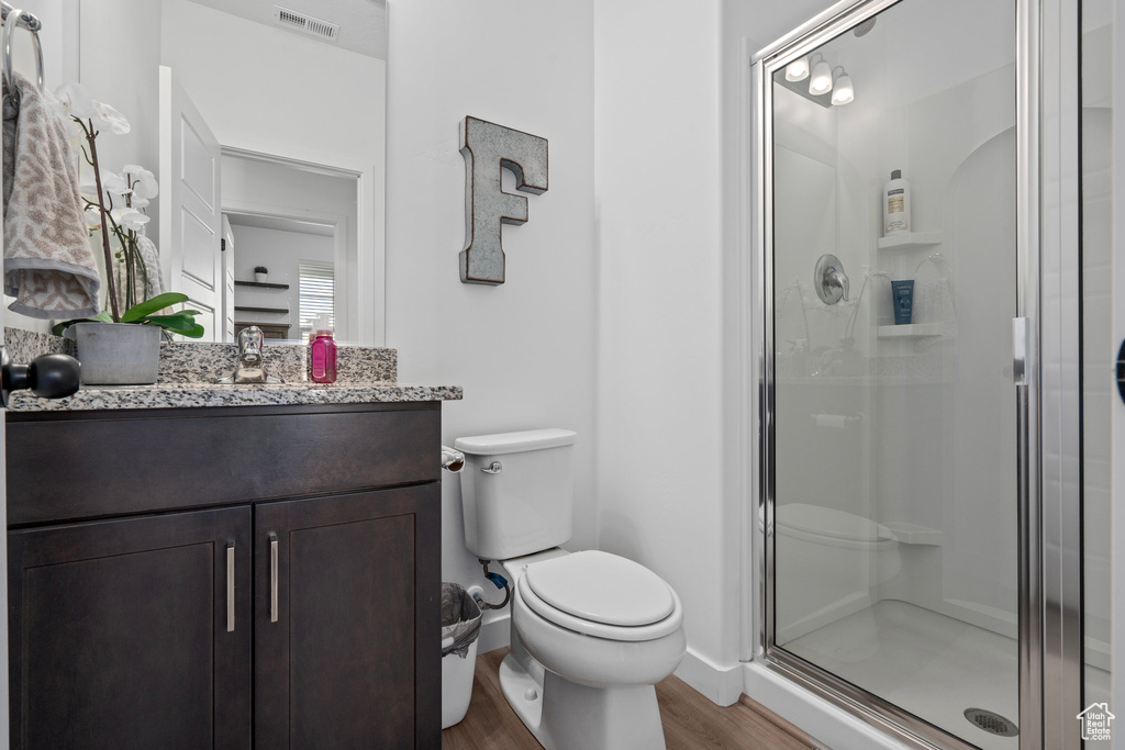 Bathroom featuring walk in shower, vanity, toilet, and hardwood / wood-style flooring