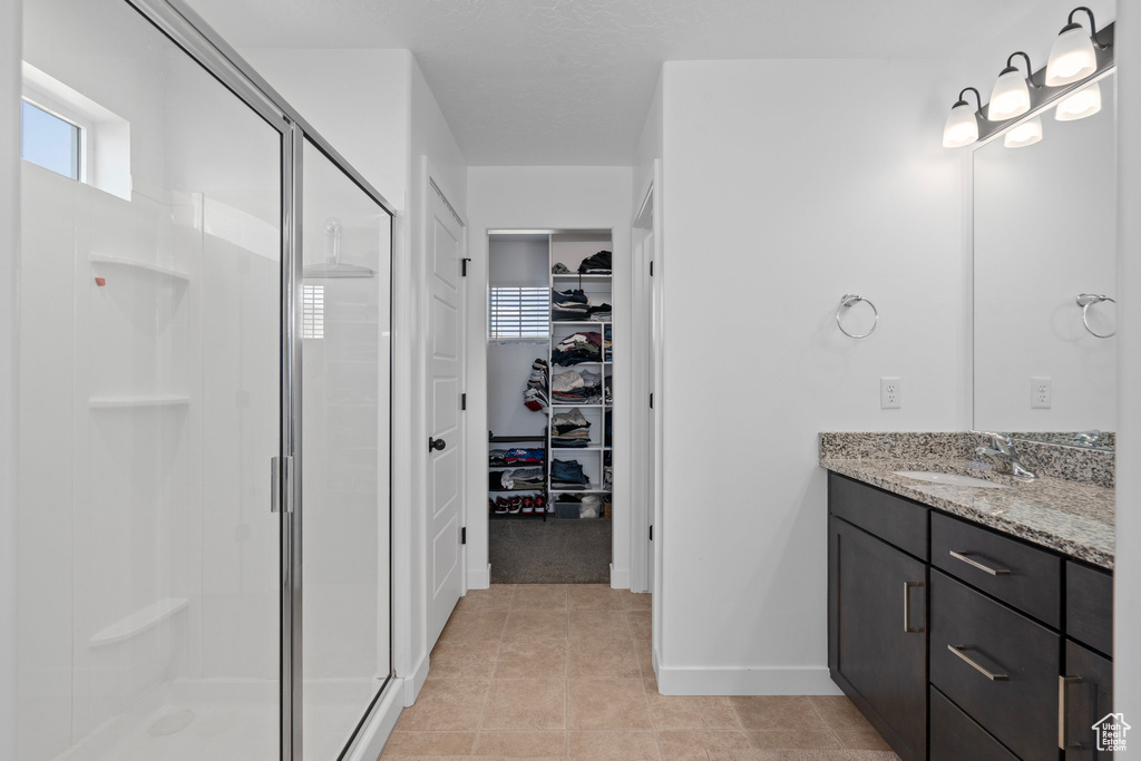 Bathroom featuring vanity, tile patterned floors, and a shower with shower door